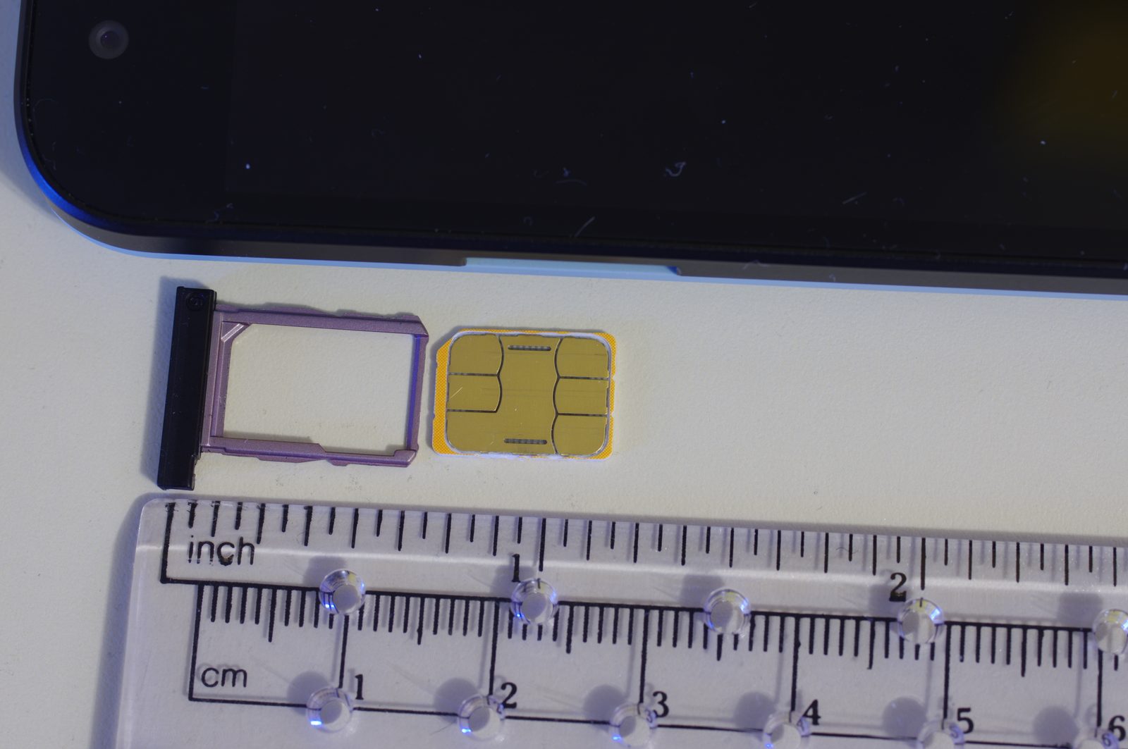 A SIM card and tray next to a ruler